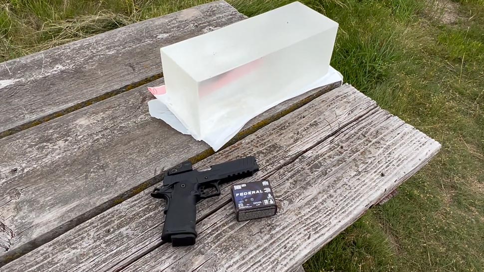 A Handgun, Box of 9mm Ammo, and Ballistic Gel on The Table