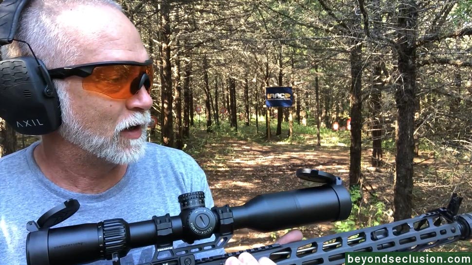 A Man Is Standing in The Woods Holding the Ruger SFAR with The Optic and Magpul Iron Sights